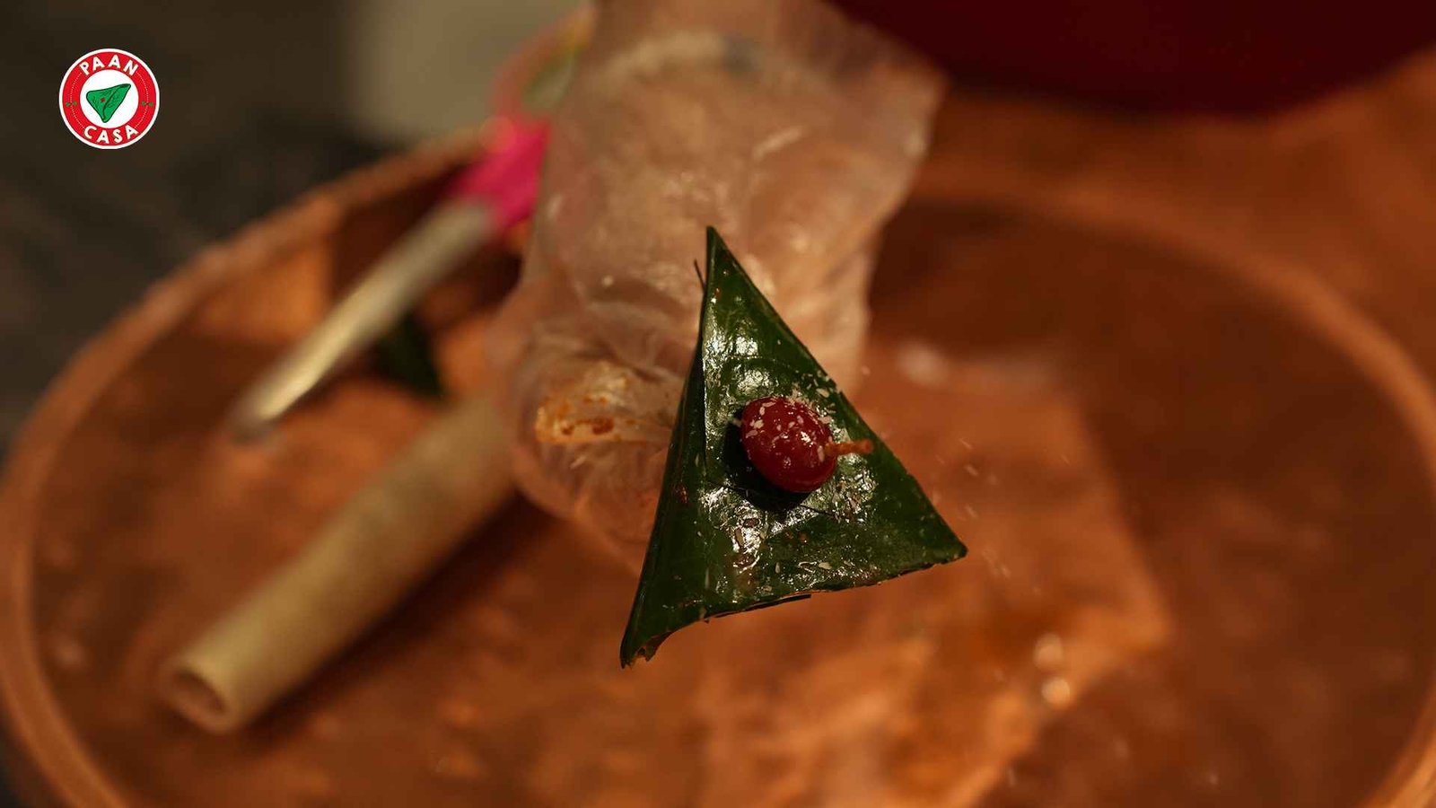 Traditional Indian paan served on a decorative leaf with a cherry garnish, showcasing a creative paan presentation.