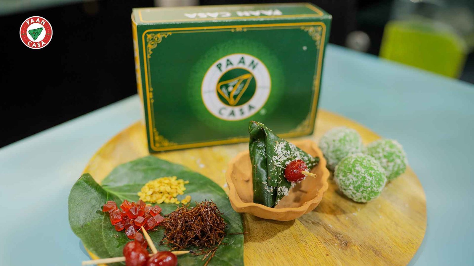 Premium paan ingredients and coconut-covered paan balls displayed on a table.