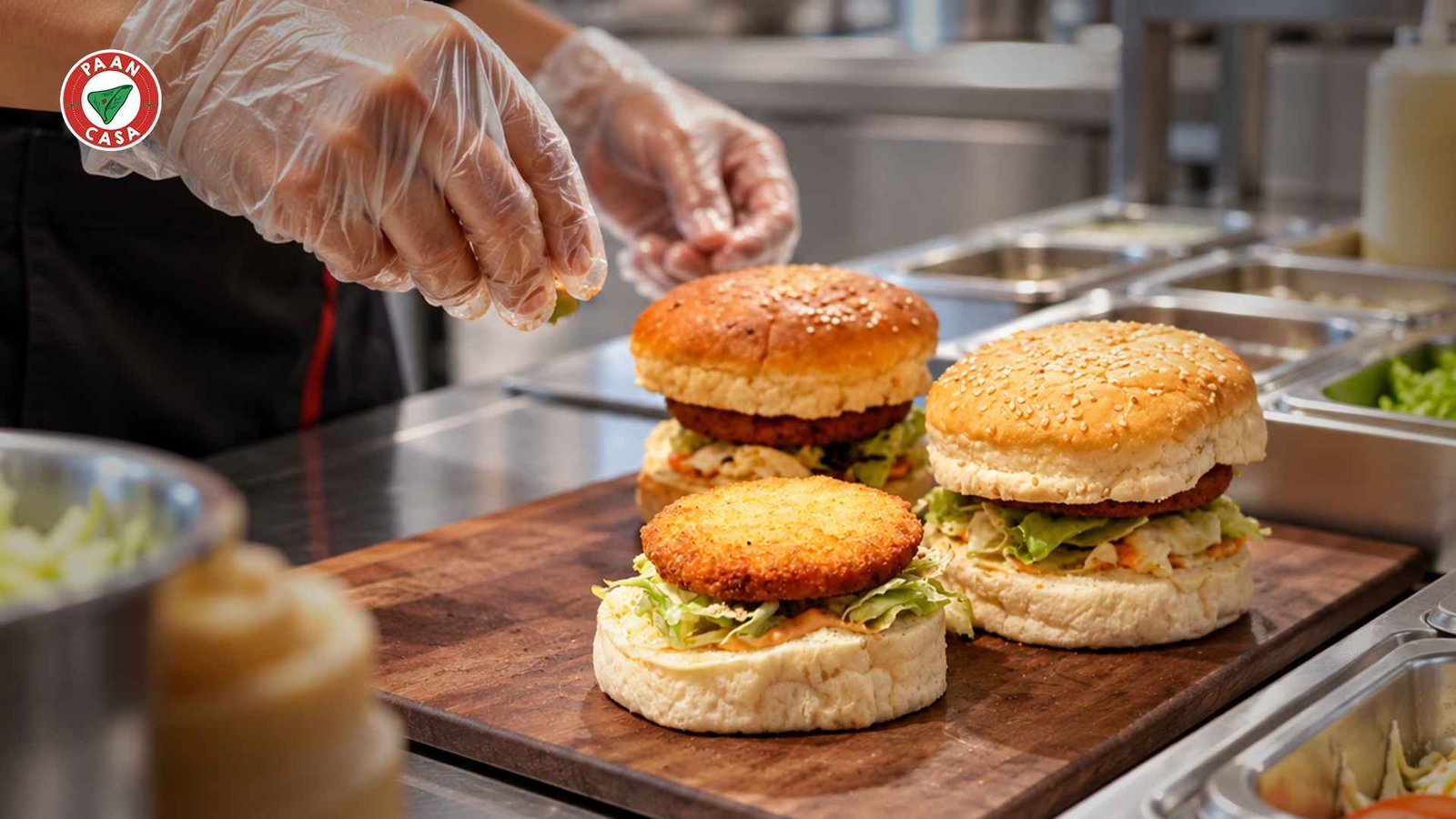 Chef preparing fresh burgers with clean gloves at a cafe kitchen.