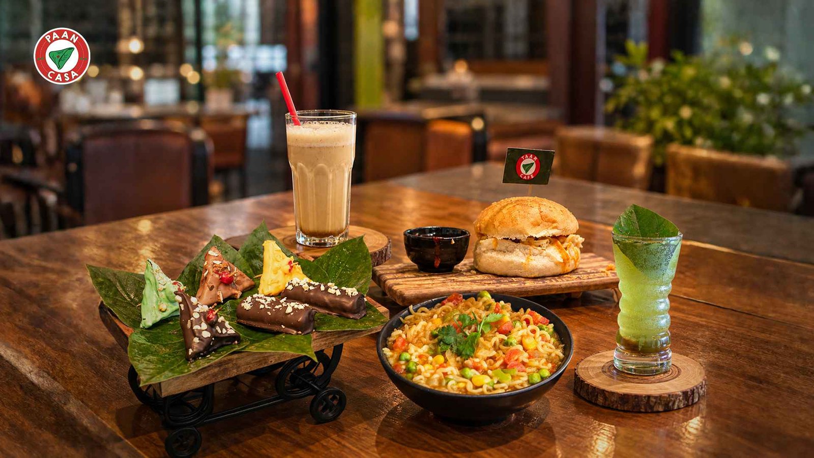 Paan Casa signature dishes, burgers, beverages, and paan desserts displayed on a wooden table.